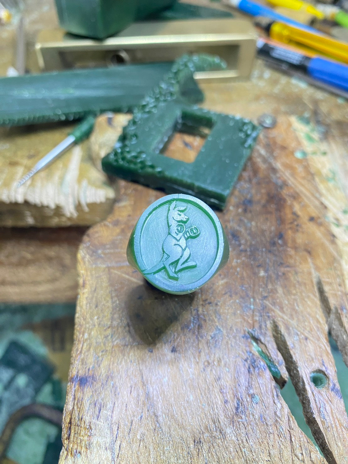 Green Boxing Kangaroo wax mold on a wooden surface with tools in the background