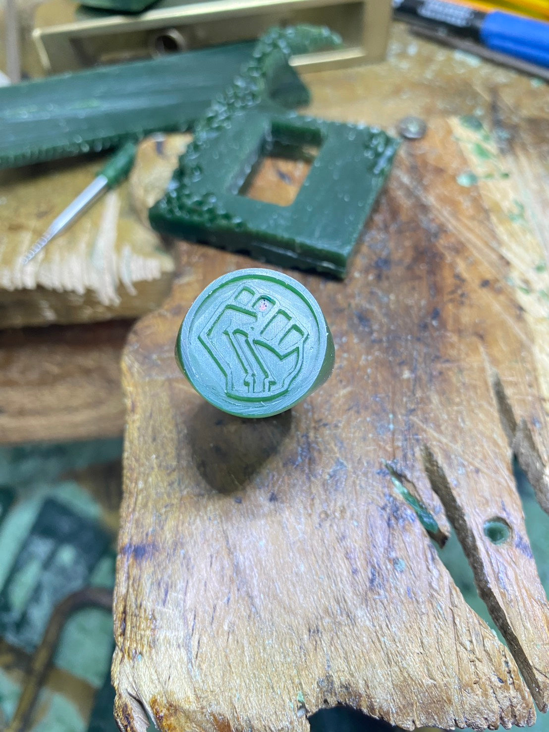 Irish Fist Green Wax Mold on a wooden surface with tools in the background